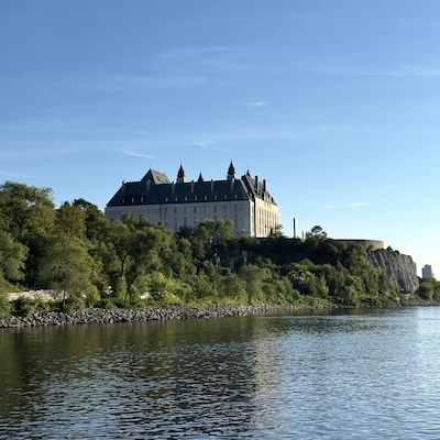 Édifice de la Cour suprême du Canada entouré d’arbres au-dessus de la rivière des Outaouais.